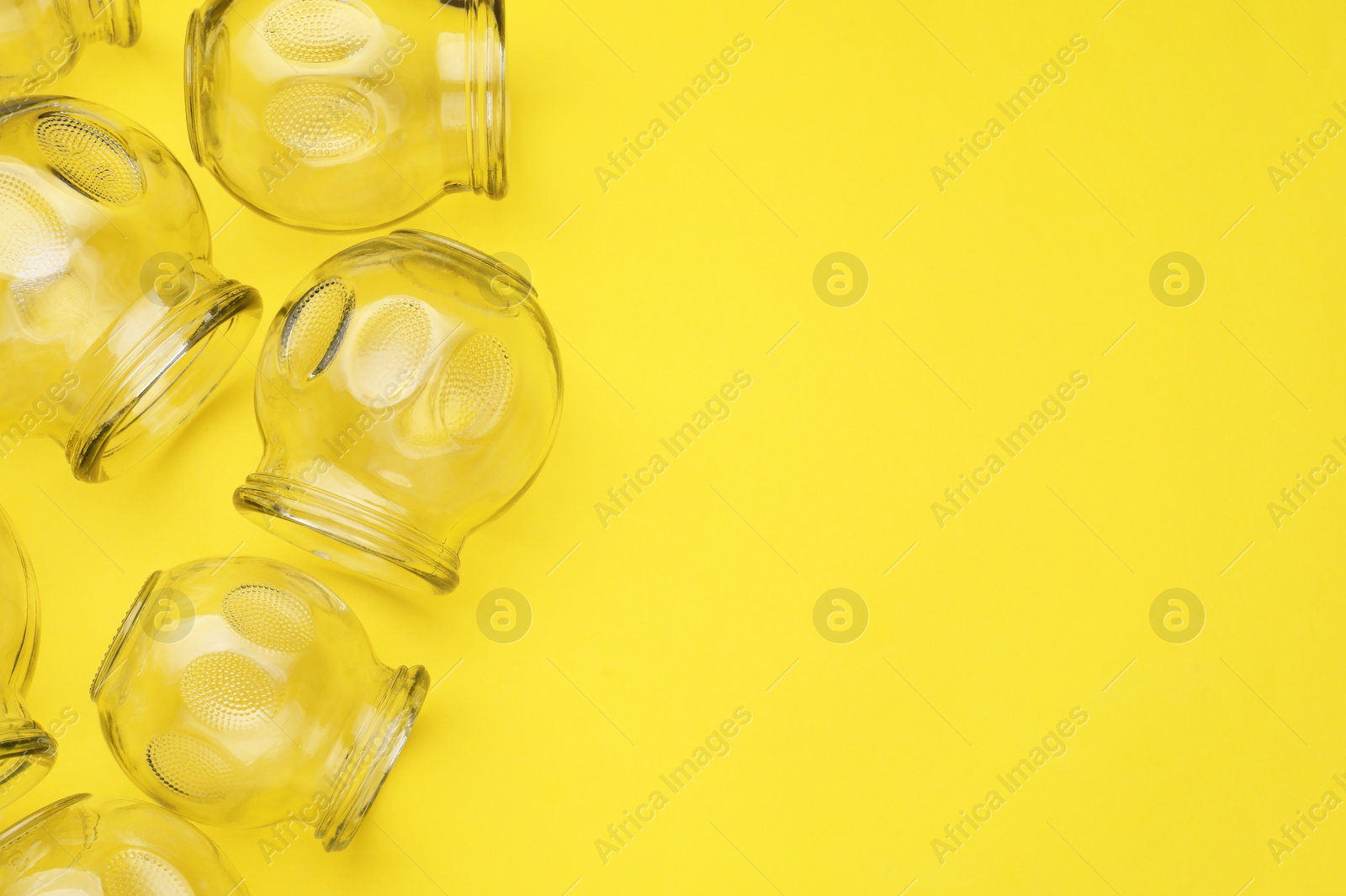 Photo of Glass cups on yellow background, flat lay and space for text. Cupping therapy