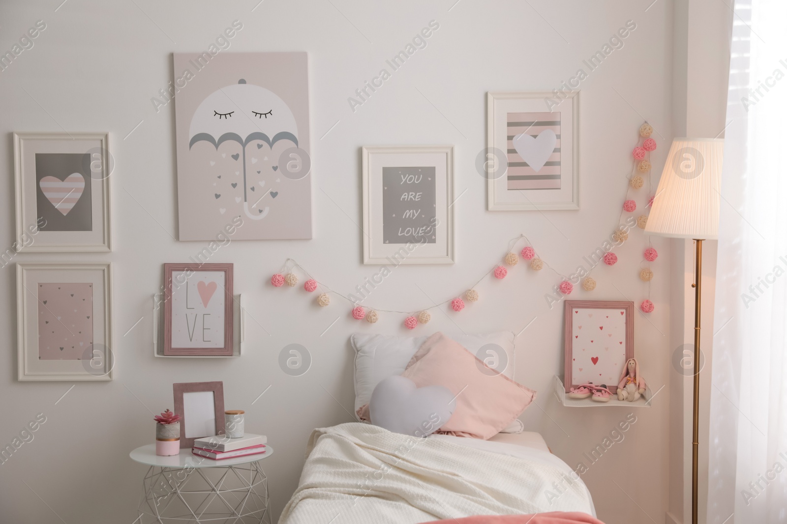 Photo of Stylish child's room interior with beautiful pictures and comfortable bed