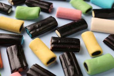 Photo of Many tasty liquorice candies on light blue background, closeup