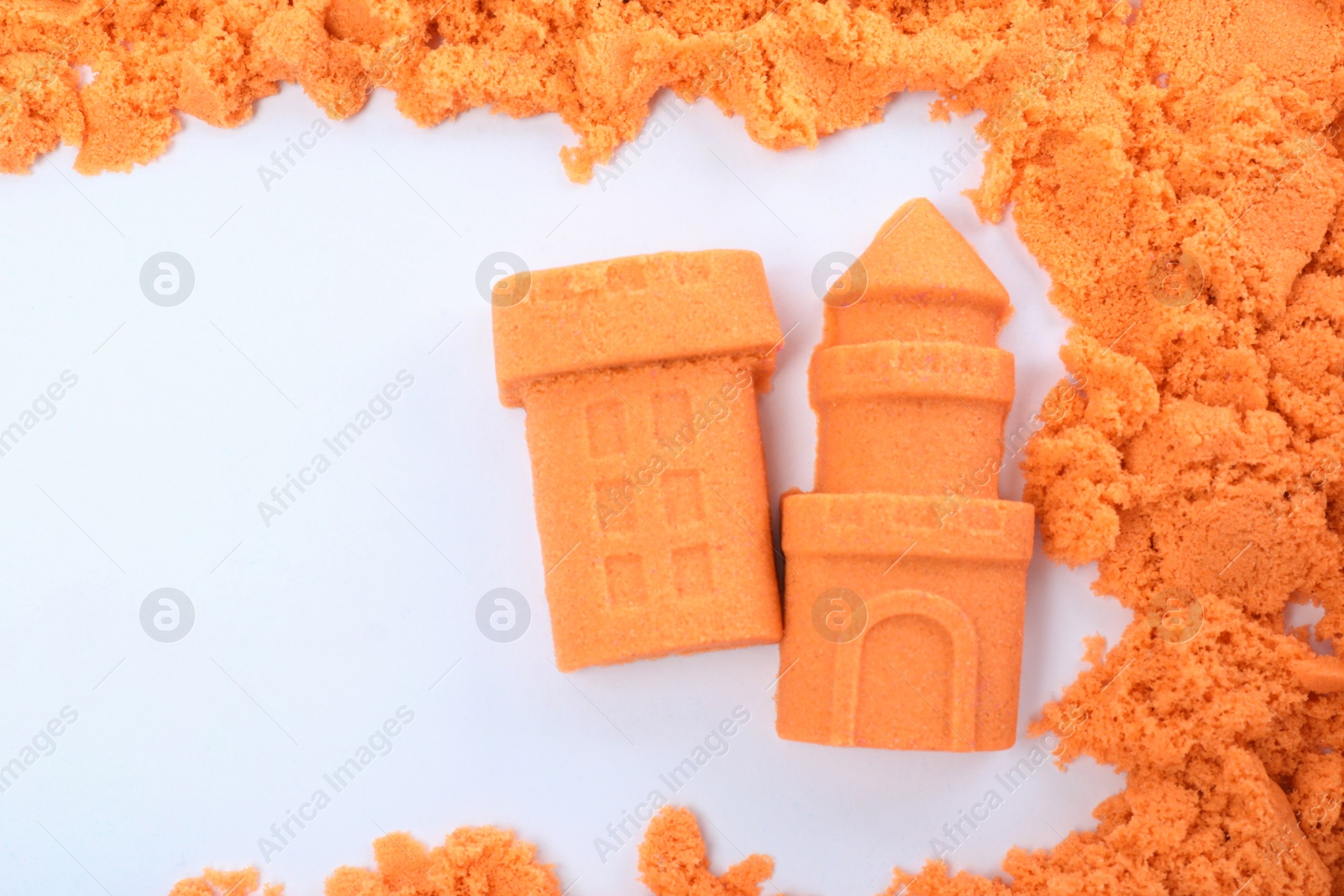 Photo of Castle and tower made of kinetic sand on white background, top view