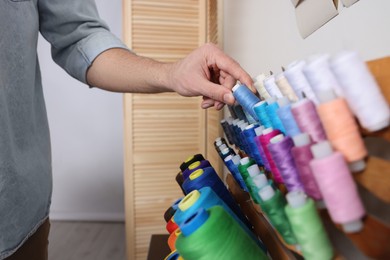 Dressmaker choosing thread in workshop, closeup view