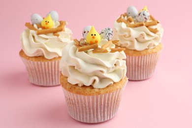 Photo of Tasty Easter cupcakes with vanilla cream on pink background, closeup