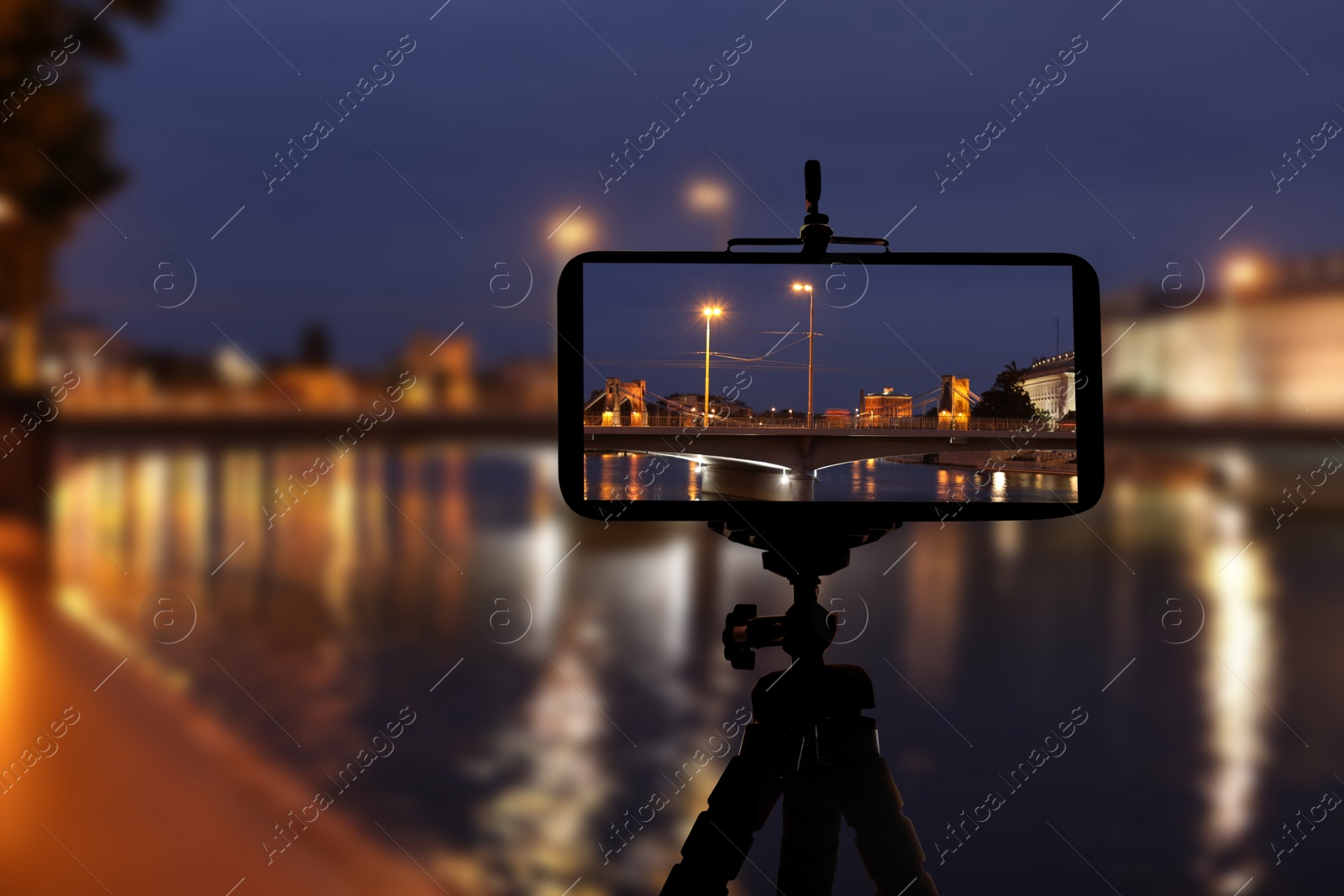 Image of Taking photo of beautiful cityscape at night with smartphone mounted on tripod