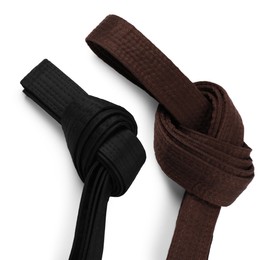 Photo of Brown and black karate belts on white background, top view
