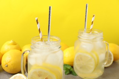 Natural freshly made lemonade on yellow background, closeup. Summer refreshing drink