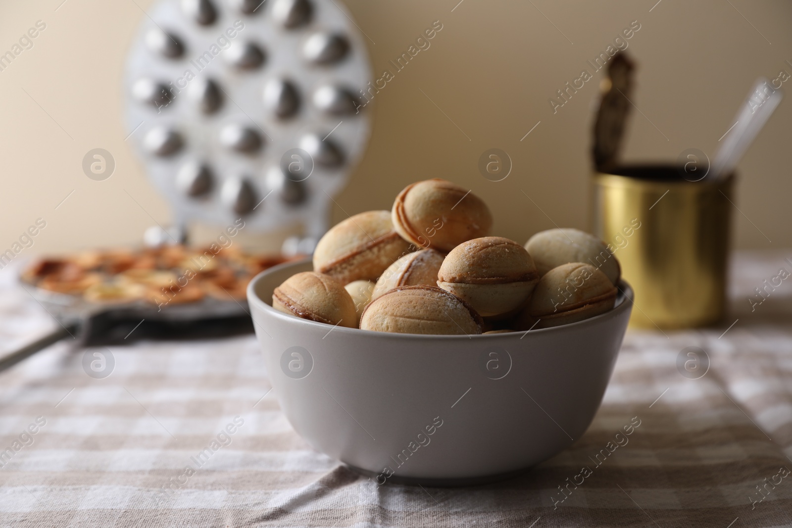 Photo of Bowl of delicious walnut shaped cookies with condensed milk on checkered tablecloth