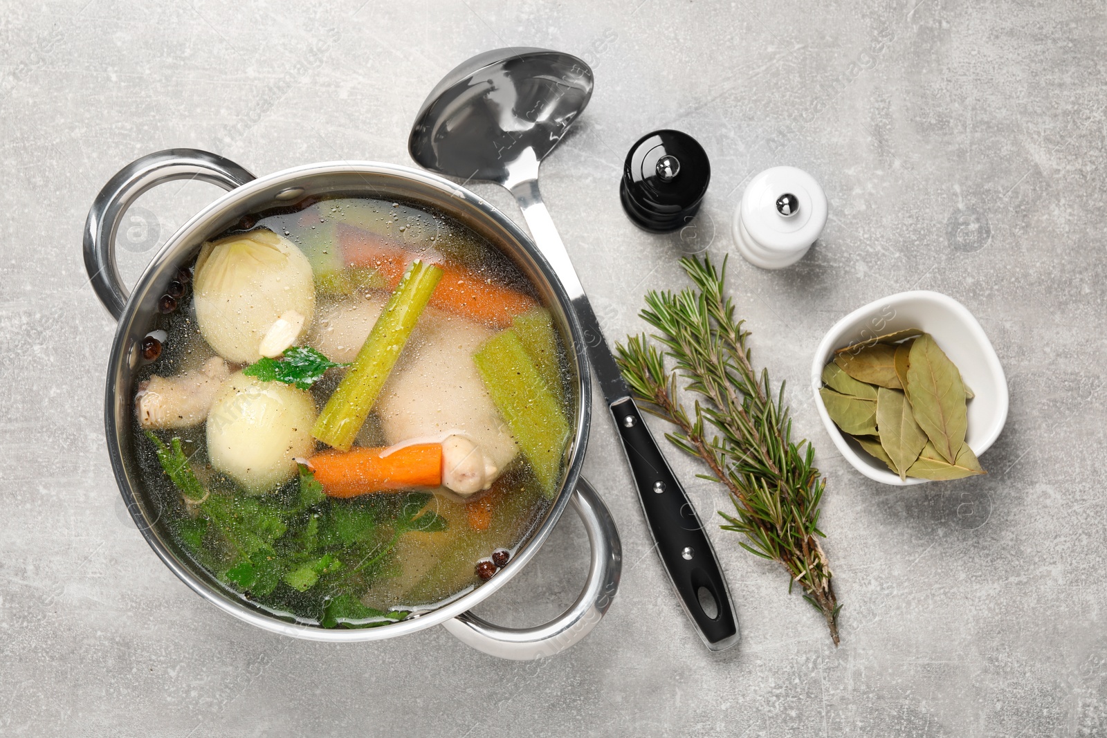 Photo of Pot with tasty bouillon and different ingredients on light grey table, flat lay