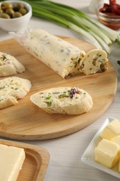 Photo of Tasty butter with olives, green onion and bread on wooden table