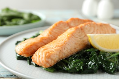 Photo of Tasty salmon with spinach and lemon on plate, closeup