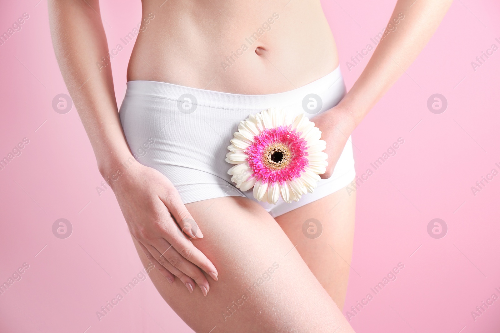 Photo of Young woman holding flower near underwear on color background. Gynecology