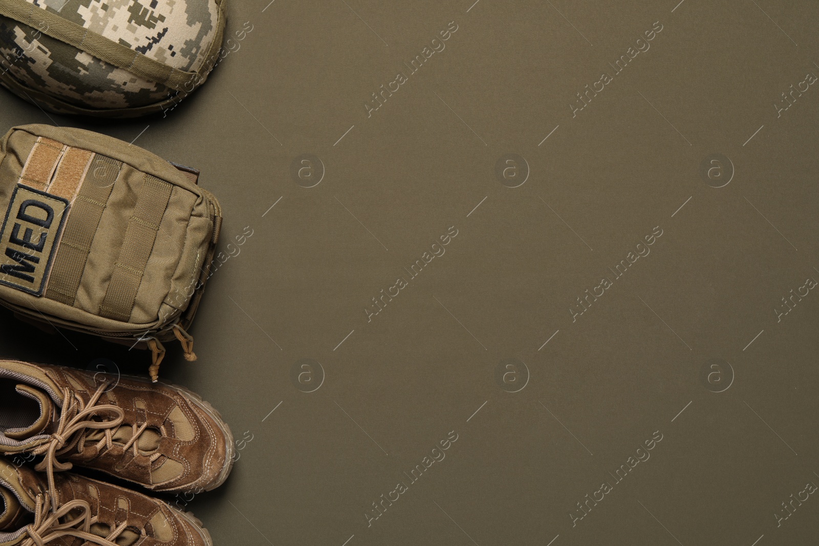 Photo of First aid kit, army boots and helmet on khaki background, flat lay. Space for text