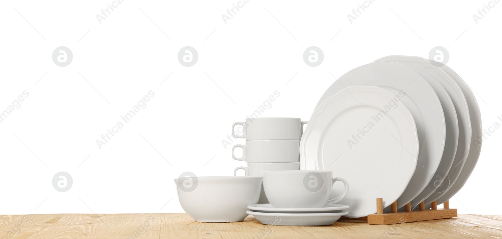 Photo of Set of different clean dishware on wooden table against white background