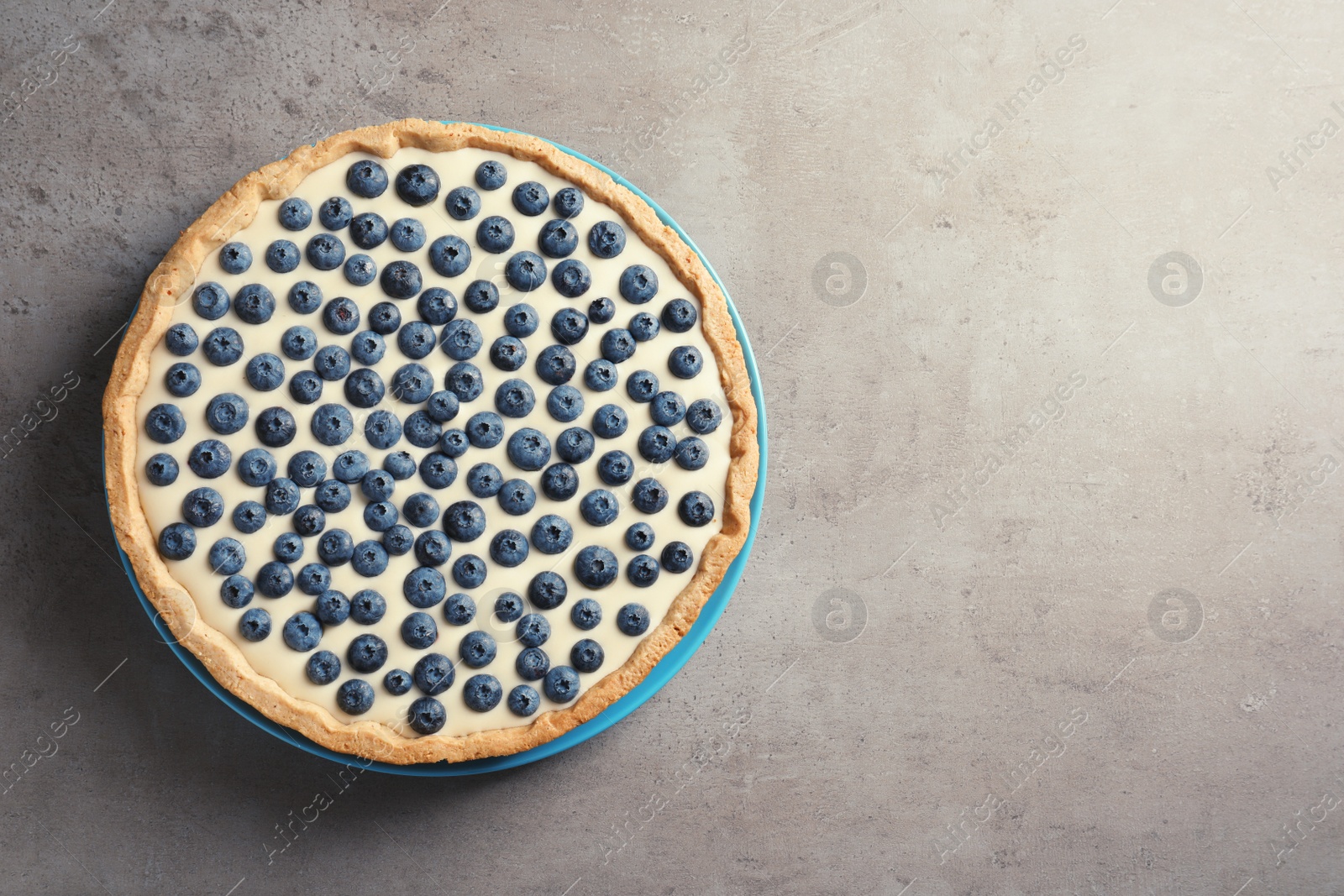 Photo of Tasty blueberry cake on gray background, top view with space for text