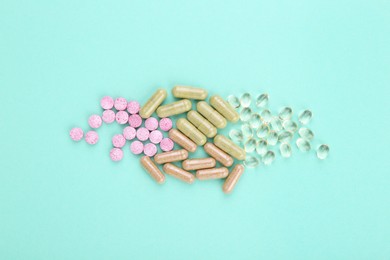 Photo of Many different vitamin pills on turquoise background, flat lay
