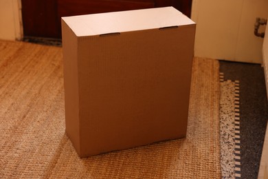 Photo of Delivery service. One cardboard on rug indoors