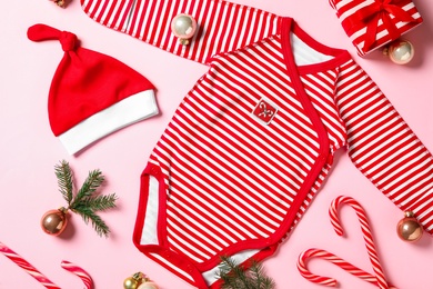 Flat lay composition with cute Christmas baby clothes on pink background