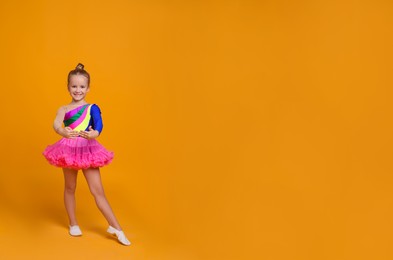 Cute little girl in costume dancing on orange background. Space for text