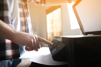 Photo of Man using modern multifunction printer in office, closeup