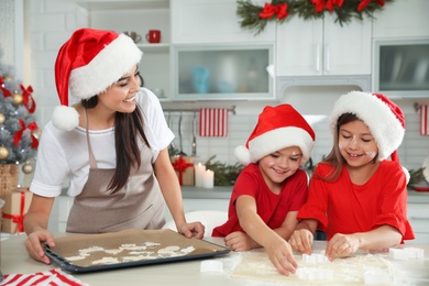 Happy family with Santa hats cooking in kitchen. Christmas time