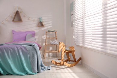 Comfortable bed with pink linens in children's room