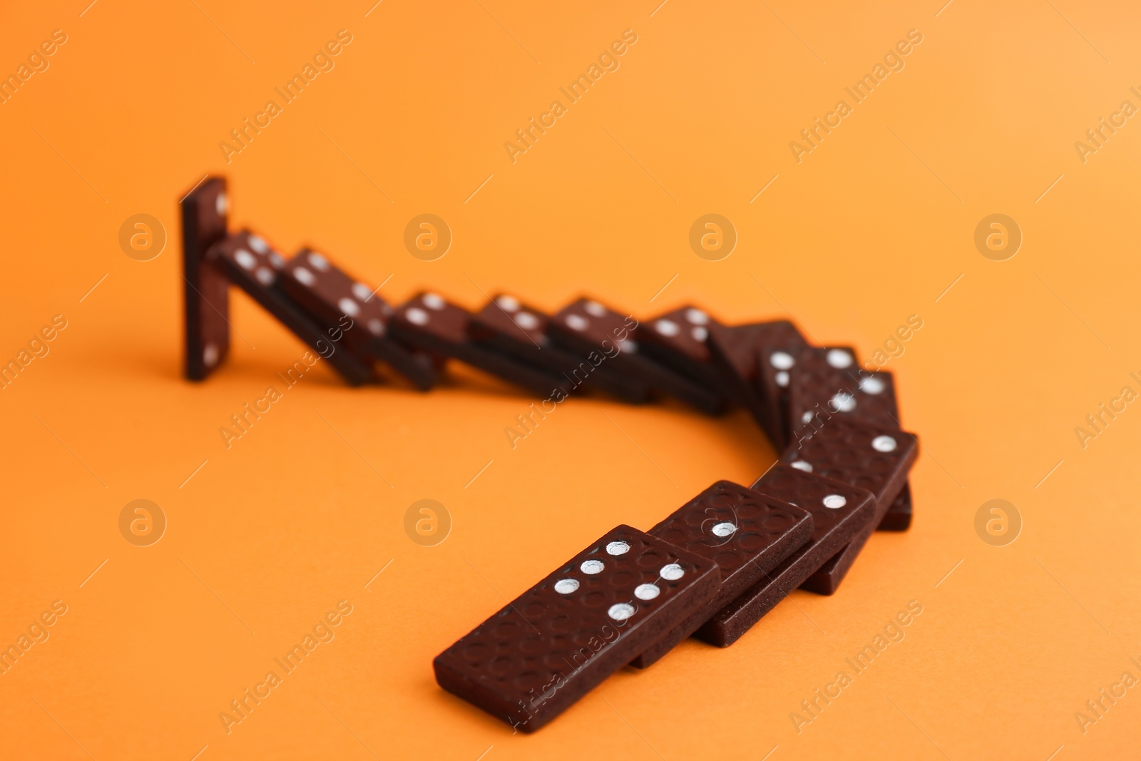 Photo of Brown domino tiles falling on orange background