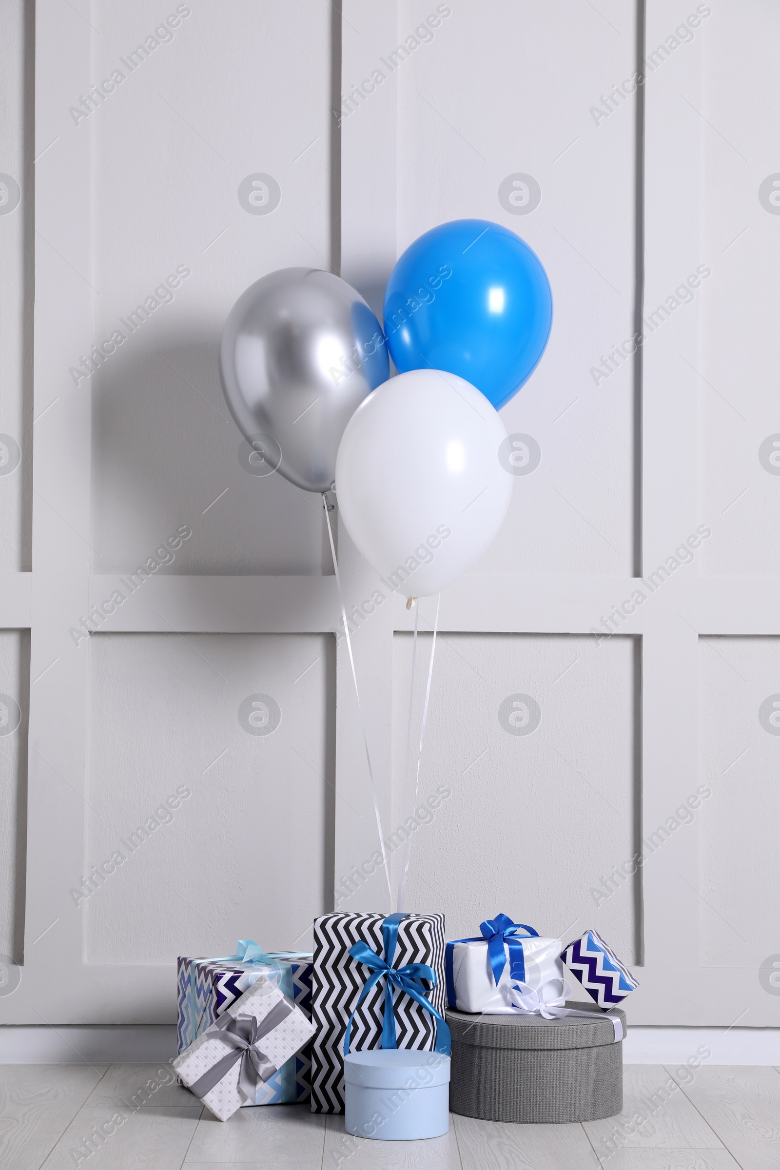Photo of Many gift boxes and balloons near white wall