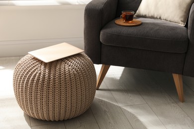 Photo of Laptop on stylish comfortable pouf in room. Home design