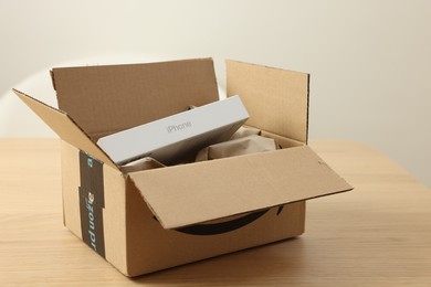 Leiden, Netherlands - October 6, 2023: New iPhone 15 Pro Max and crumpled paper in cardboard box on wooden table. Amazon delivery