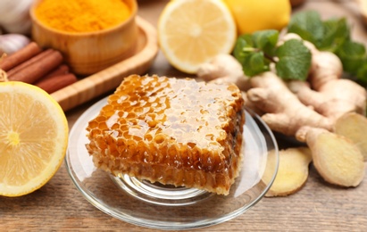 Photo of Fresh honeycomb and other products on wooden table, closeup. Natural antibiotics