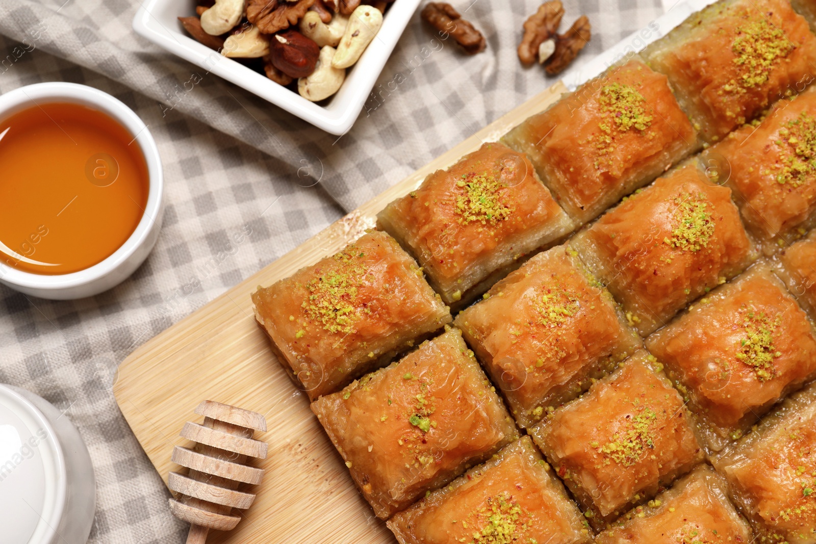 Photo of Delicious sweet baklava with nuts and honey on table, flat lay