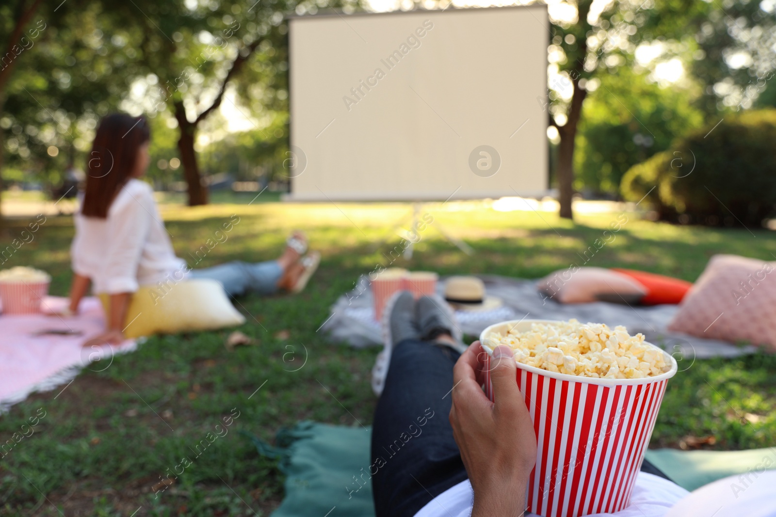 Photo of Young man with popcorn watching movie in open air cinema, closeup. Space for text