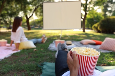 Young man with popcorn watching movie in open air cinema, closeup. Space for text