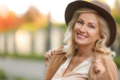 Portrait of happy mature woman with hat outdoors