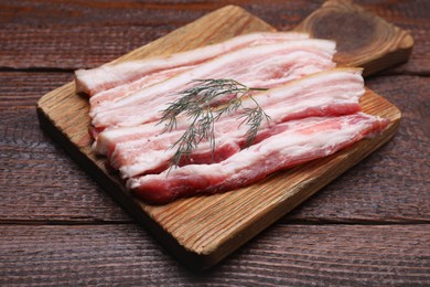 Slices of tasty pork fatback with dill on wooden table, closeup
