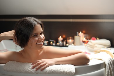 Photo of Happy beautiful woman taking bath indoors. Romantic atmosphere