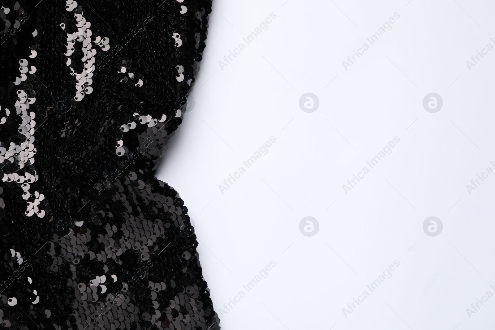Photo of Black shiny sequin fabric on white background, top view. Space for text
