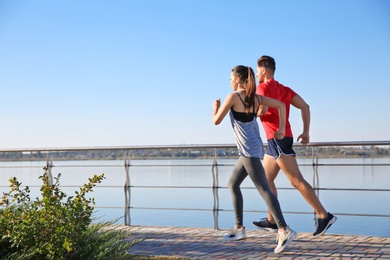 Photo of Sporty couple running outdoors on sunny morning
