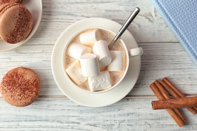 Photo of Tasty cocoa drink with marshmallows in cup on wooden table, top view