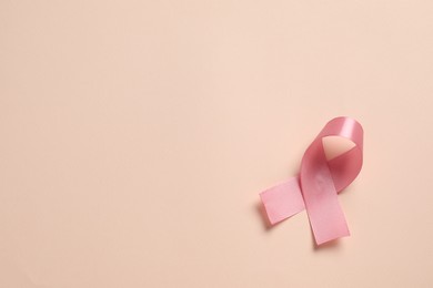 Photo of Pink ribbon on beige background, top view and space for text. Breast cancer awareness