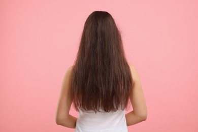 Photo of Woman with damaged hair before treatment on pink background, back view
