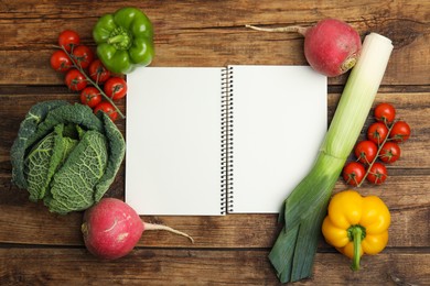 Photo of Recipe book surrounded by different fresh vegetables on wooden table, flat lay with space for text. Cooking classes