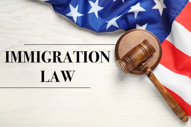 Immigration law. Judge's gavel and American flag on white wooden table, top view