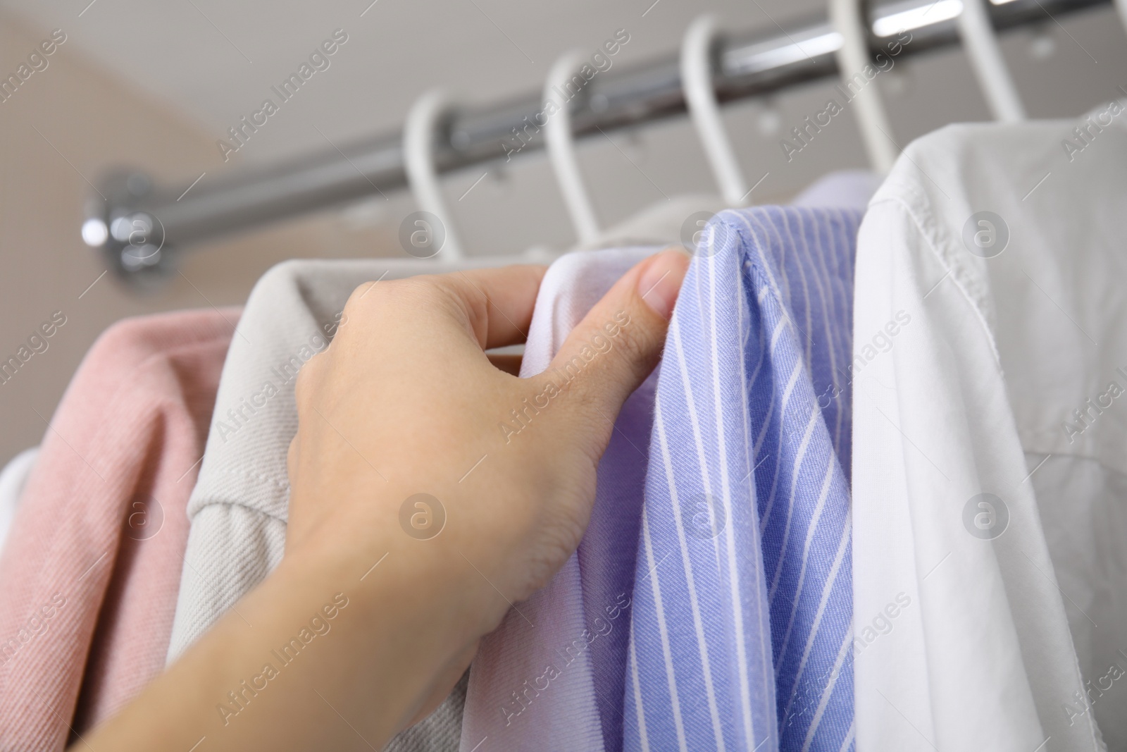 Photo of Woman choosing clothes from wardrobe rod, closeup