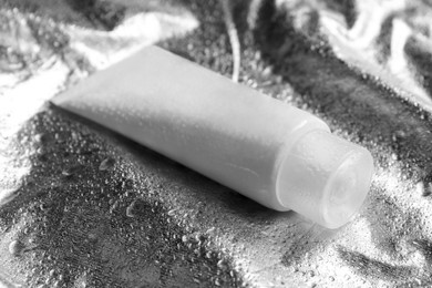 Photo of Tube with face cleansing product on silver background, closeup