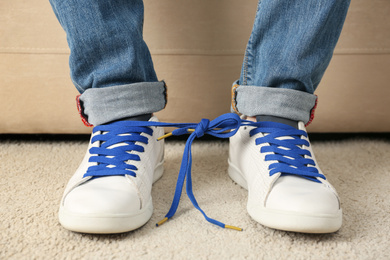 Man wearing sneakers with tied together laces, closeup. April fool's day