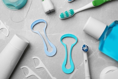 Flat lay composition with tongue cleaners and teeth care products on grey background