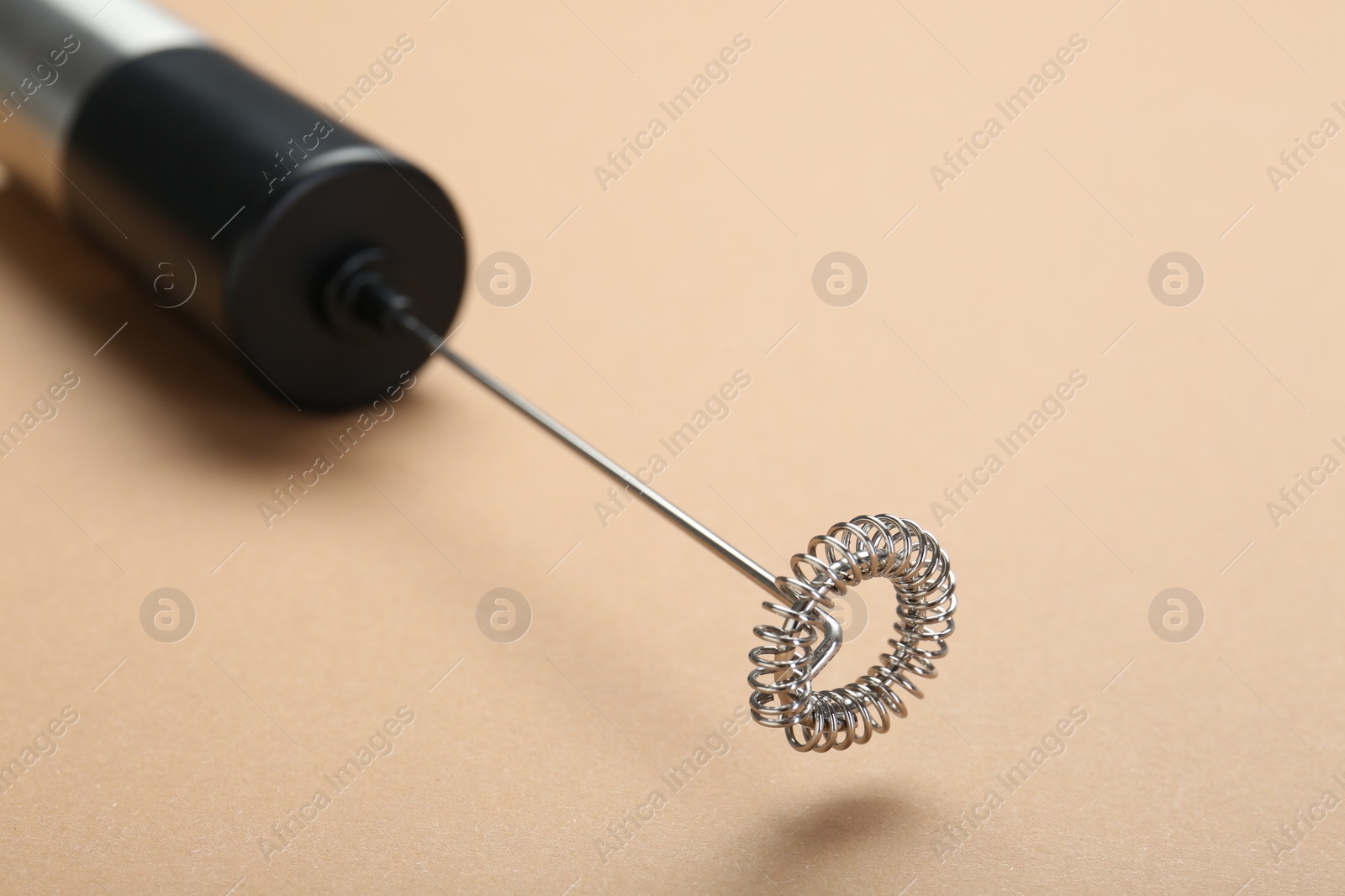 Photo of Milk frother wand on light brown background, closeup