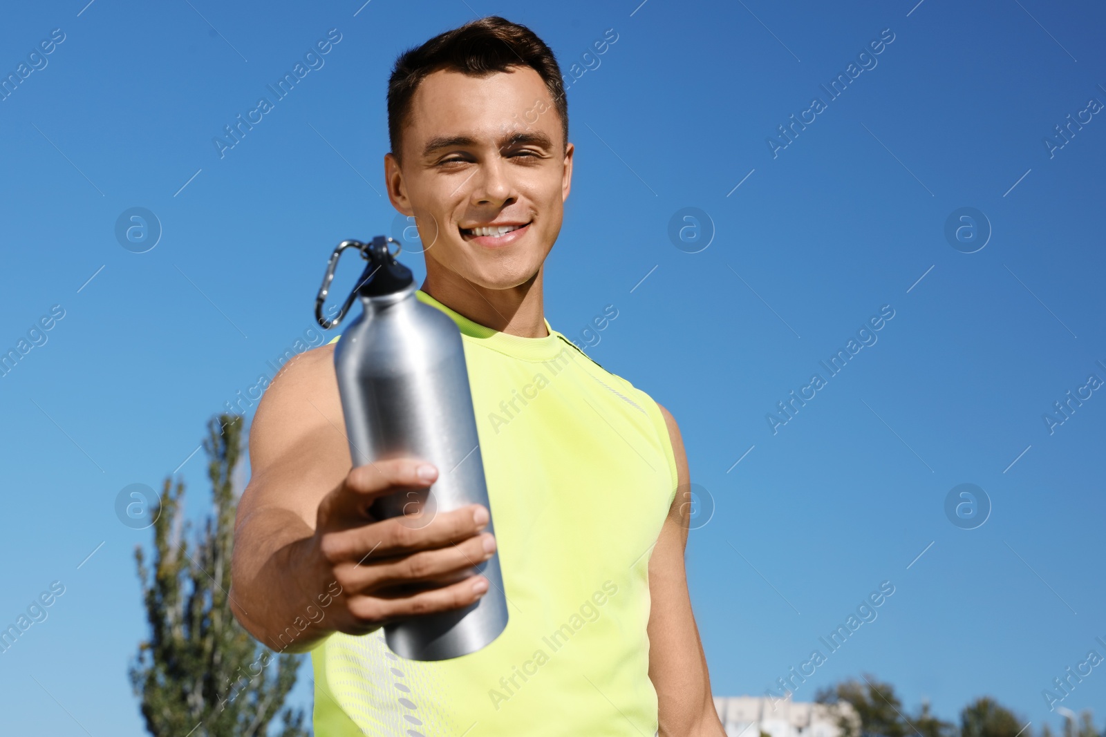 Photo of Sporty man with bottle of water outdoors on sunny day. Space for text