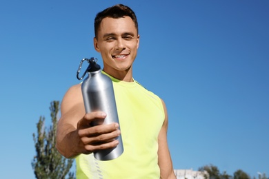 Photo of Sporty man with bottle of water outdoors on sunny day. Space for text