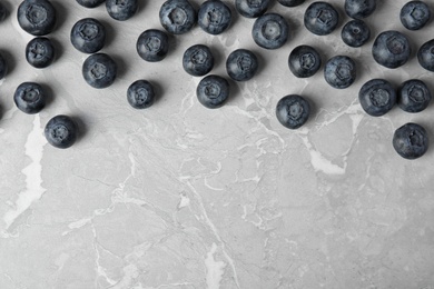 Tasty fresh blueberries on grey marble table, top view with space for text